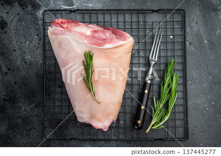 Raw pork knuckle on cooling rack with rosemary on dark stone surface perfect for cooking guides butchery visuals and recipe content. 137445277
