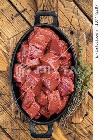 Fresh diced beef calf liver prepared for cooking in skillet on wooden background. Traditional offal ingredient Fresh diced beef calf liver prepared for cooking in skillet on wooden background. Traditional offal ingredient 137445297