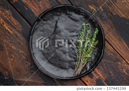 Empty ceramic plate with herbs on dark wood background. Rustic minimalist food mockup with copy space for menu and banners. 137445299