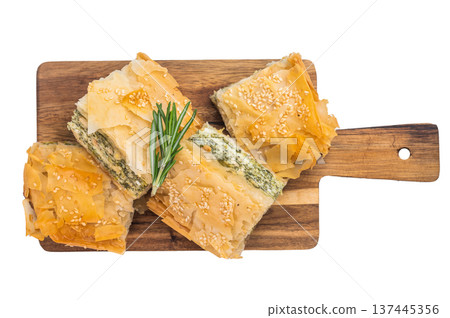 Crispy phyllo pastry squares with spinach and cheese filling on wooden board, flaky layers with sesame seeds Crispy phyllo pastry squares with spinach and cheese filling on wooden board, flaky layers with sesame seeds 137445356