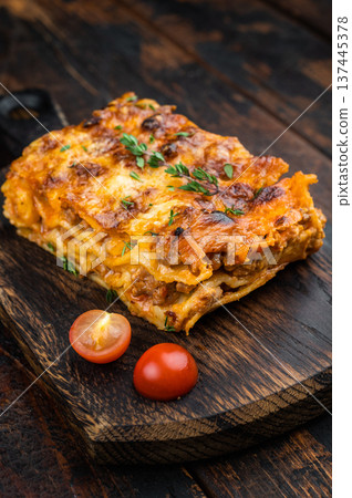 Homemade beef lasagna portion with rich bolognese sauce pasta sheets and cheesy crust on rustic board Homemade beef lasagna portion with rich bolognese sauce pasta sheets and cheesy crust on rustic board 137445378