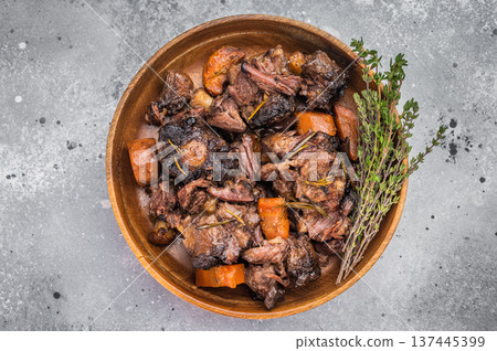 Braised veal oxtail stew with carrots and herbs served in wooden bowl, tender slow cooked meat in rich sauce Braised veal oxtail stew with carrots and herbs served in wooden bowl, tender slow cooked meat in rich sauce 137445399