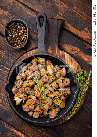 Fried chicken hearts with herbs and spices in skillet on wooden background perfect for rustic culinary photography. 137445402