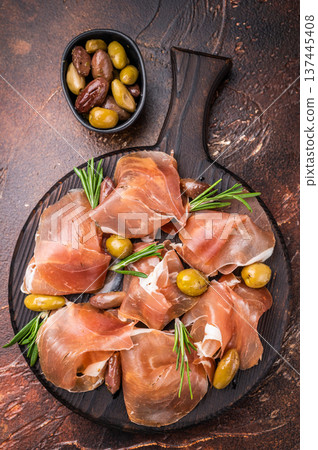Appetizing plate of thinly sliced cured Spain ham Jamon garnished with rosemary sprigs. Top view food stock. Appetizing plate of thinly sliced cured Spain ham Jamon garnished with rosemary sprigs. Top view food stock. 137445408