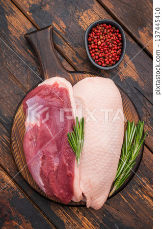 Raw duck breasts skin on and skinless with rosemary and pepper on rustic wooden board ideal for gourmet poultry cooking stock images. Raw duck breasts skin on and skinless with rosemary and pepper on rustic wooden board ideal for gourmet poultry cooking stock images. 137445410