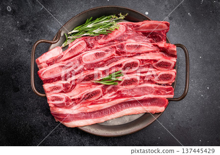 Raw Flanken cut beef short ribs (Kalbi) with rosemary and thyme on a dark, rustic background. Copy space. Raw Flanken cut beef short ribs (Kalbi) with rosemary and thyme on a dark, rustic background. Copy space. 137445429