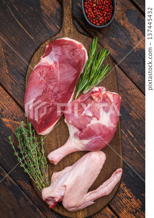 Plucked raw duck meat selection displayed on rustic board with seasoning against dark wood backdrop showcasing premium poultry. Plucked raw duck meat selection displayed on rustic board with seasoning against dark wood backdrop showcasing premium poultry. 137445432