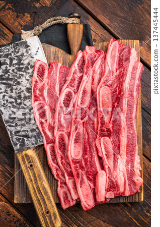 Premium quality raw cross-cut short ribs ready for preparation, set against a dark, rustic wood backdrop. Premium quality raw cross-cut short ribs ready for preparation, set against a dark, rustic wood backdrop. 137445444