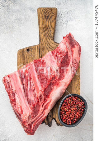 Uncooked beef ribs with fat and muscle texture on wooden board. Light background with copy space for food industry and recipes Uncooked beef ribs with fat and muscle texture on wooden board. Light background with copy space for food industry and recipes 137445476