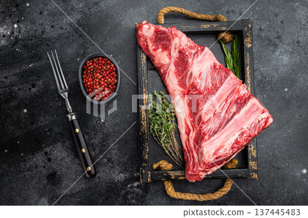 resh raw beef ribs slab with thyme and rosemary on wooden tray. Butcher meat cut on dark textured background with copy space. 137445483
