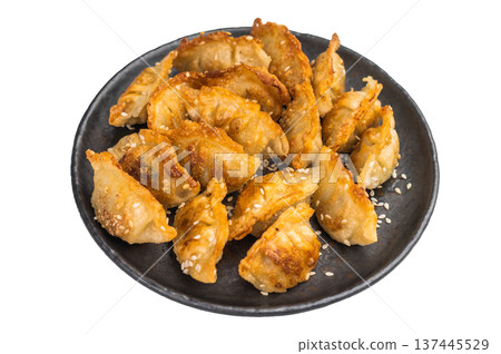 Crispy pan fried jiaozi dumplings with sesame served on dark plate. Asian mandu potstickers photographed top view on light background. Crispy pan fried jiaozi dumplings with sesame served on dark plate. Asian mandu potstickers photographed top view on light background. 137445529