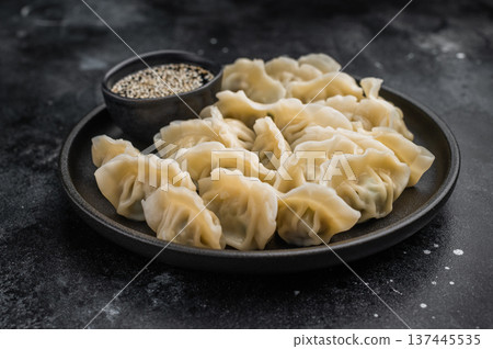 Tasty steamed gyoza wontons arranged on a black plate over concrete background. Authentic asian appetizer for menus and culinary projects. 137445535