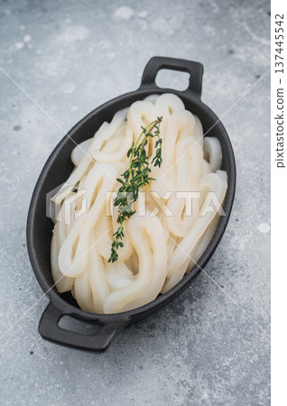 Fresh calamari rings in cast iron bowl with thyme on textured gray background ideal seafood ingredient for gourmet cooking. Fresh calamari rings in cast iron bowl with thyme on textured gray background ideal seafood ingredient for gourmet cooking. 137445542