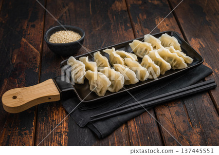 Homemade Asian potstickers neatly placed on a serving tray. Classic dumplings from Chinese, Japanese or Korean cuisine. Minimalistic composition ideal for culinary promotion and editorial use. Homemade Asian potstickers neatly placed on a serving tray. Classic dumplings from Chinese, Japanese or Korean cuisine. Minimalistic composition ideal for culinary promotion and editorial use. 137445551