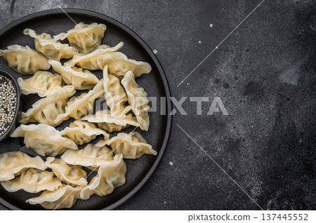 Fresh asian dumplings mandu served on a dark textured surface. Minimal food composition ideal for restaurant ads and stock use. Fresh asian dumplings mandu served on a dark textured surface. Minimal food composition ideal for restaurant ads and stock use. 137445552