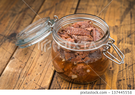 Rustic venison preserved stew in a glass jar with garlic, thyme and pepper on a wooden board. Hearty wildgame meat with rich slowcooked flavor. 137445558