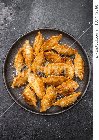 Crunchy gyoza wonton dumplings on dark stone background savory Asian dish with golden crust and sesame garnish 137445560