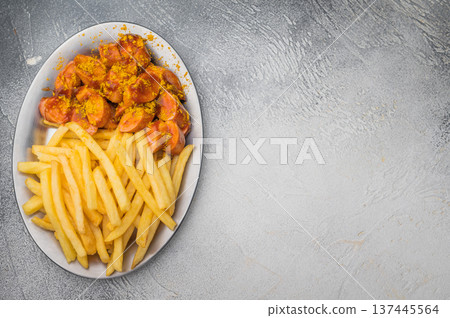 German currywurst with crispy fries on metal plate over wooden board and concrete background ideal for street food ads and stock images. German currywurst with crispy fries on metal plate over wooden board and concrete background ideal for street food ads and stock images. 137445564