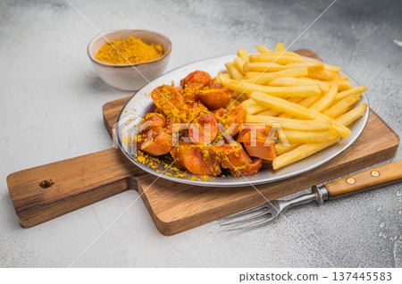 German currywurst with crispy fries on metal plate over wooden board and concrete background ideal for street food ads and stock images. 137445583