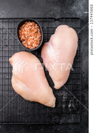 Fresh chicken breasts, beautifully displayed, showcasing their tender texture. Perfect for marinating and cooking your favorite dishes. black background. top view Fresh chicken breasts, beautifully displayed, showcasing their tender texture. Perfect for marinating and cooking your favorite dishes. black background. top view 137445668