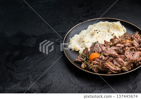 Beef stew with mashed potatoes, carrots and herbs on a plate isolated. black background. top view Beef stew with mashed potatoes, carrots and herbs on a plate isolated. black background. top view 137445674
