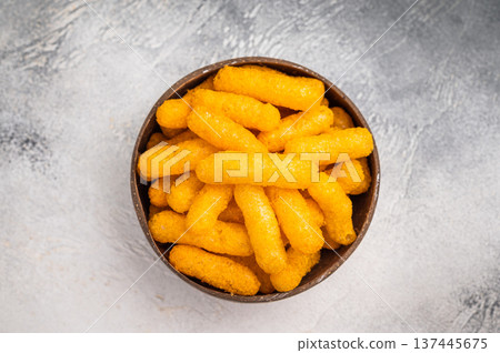 Irresistible Cheese puffs, cheese snacks bursting with bold flavors and a satisfying crunch. grey background. top view Irresistible Cheese puffs, cheese snacks bursting with bold flavors and a satisfying crunch. grey background. top view 137445675