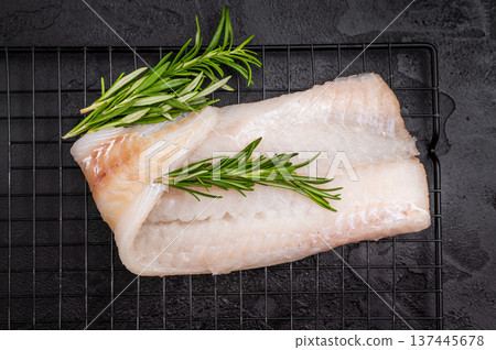 Uncooked Atlantic cod fillet, raw fish ready to be seasoned and transformed into a delicious meal. black background. top view Uncooked Atlantic cod fillet, raw fish ready to be seasoned and transformed into a delicious meal. black background. top view 137445678