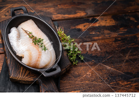 Pristine raw cod fillet, waiting to be marinated and cooked to perfection for a delightful dining experience. wooden background. top view Pristine raw cod fillet, waiting to be marinated and cooked to perfection for a delightful dining experience. wooden background. top view 137445712