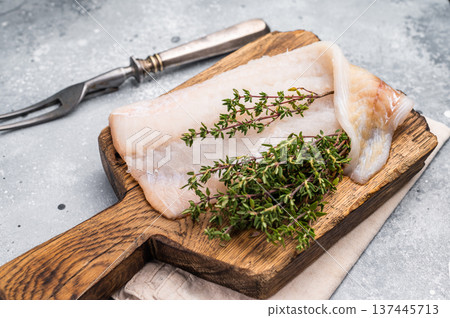 Fresh cod fish fillet, showcasing its delicate texture and pristine color, perfect for grilling or baking. grey background. top view Fresh cod fish fillet, showcasing its delicate texture and pristine color, perfect for grilling or baking. grey background. top view 137445713
