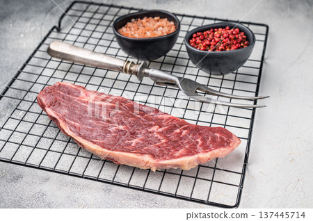 Fresh raw top sirloin steak, showcasing its rich color and marbling. grey background. top view Fresh raw top sirloin steak, showcasing its rich color and marbling. grey background. top view 137445714
