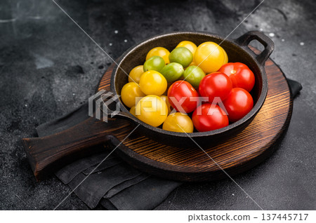 Uncooked small tomatoes. red, green and yellow cherry tomatoes assortment, cocktail mix. black background. top view Uncooked small tomatoes. red, green and yellow cherry tomatoes assortment, cocktail mix. black background. top view 137445717
