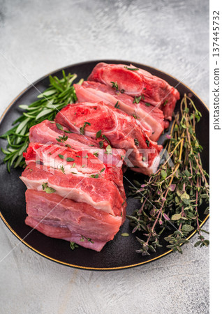 Raw Beef Kalbi Short Ribs, fresh meat with bone on plate with thyme. grey background. top view 137445732