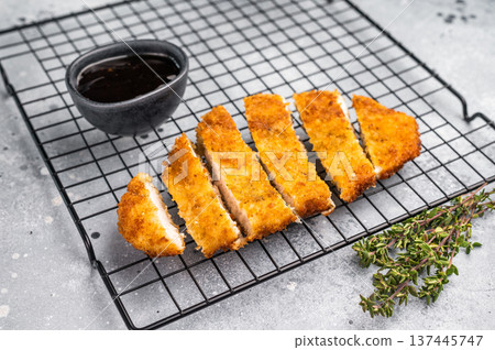 Tender chicken cutlet katsu, coated in crunchy breadcrumbs and fried to perfection. Ideal for a satisfying meal or as a topping for rice. grey background. top view Tender chicken cutlet katsu, coated in crunchy breadcrumbs and fried to perfection. Ideal for a satisfying meal or as a topping for rice. grey background. top view 137445747