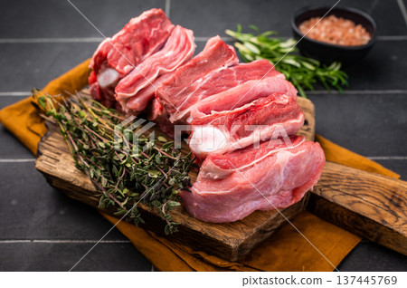 Fresh lamb rack rib pieces, mutton meat with thyme on wooden board. black background. top view Fresh lamb rack rib pieces, mutton meat with thyme on wooden board. black background. top view 137445769