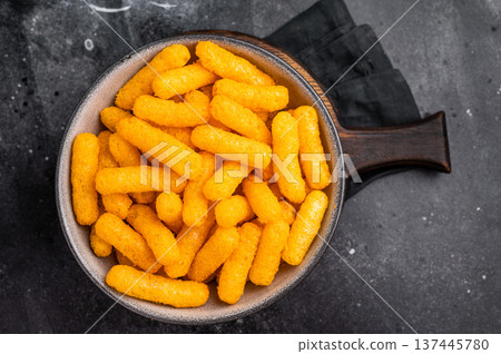 Deliciously addictive cheese flavored corn puffs, beautifully arranged on a plate. black background. top view 137445780