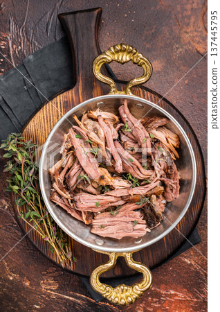 Close-up of succulent pulled brisket piled high on a rustic wooden board, garnished with fresh herbs, delicious meal. brown background. top view Close-up of succulent pulled brisket piled high on a rustic wooden board, garnished with fresh herbs, delicious meal. brown background. top view 137445795