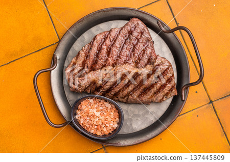 Grilled Denver steak, perfectly seared with beautiful grill marks, showcasing its juicy tenderness and rich flavor. orange background. top view Grilled Denver steak, perfectly seared with beautiful grill marks, showcasing its juicy tenderness and rich flavor. orange background. top view 137445809
