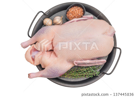 Uncooked duck carcass arranged with herbs and salt in rustic round tray against clean surface perfect for culinary food photography. 137445836