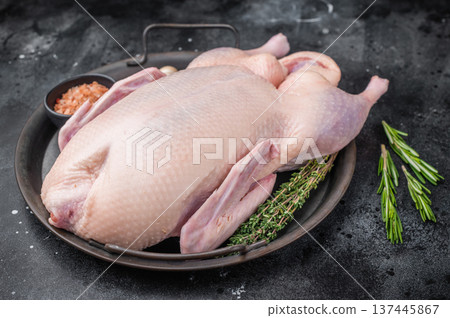 Raw whole duck with thyme garlic and pink salt on round pan over dark stone background perfect for gourmet poultry and cooking stock images. 137445867