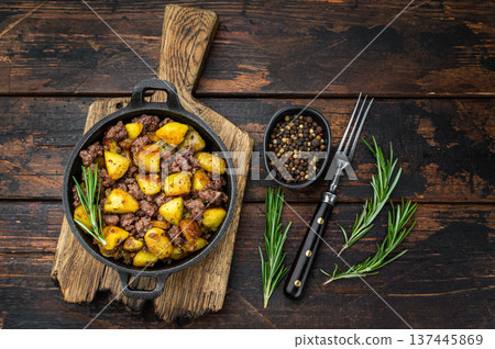 Rustic beef hash with fried potatoes served in a cast iron skillet on a wooden board perfect for comfort food and recipe visuals. 137445869