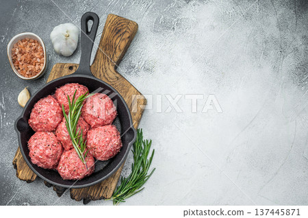 Uncooked raw meatballs Polpette style with garlic and salt in black skillet highlighting raw texture perfect for culinary and butcher visuals. Uncooked raw meatballs Polpette style with garlic and salt in black skillet highlighting raw texture perfect for culinary and butcher visuals. 137445871