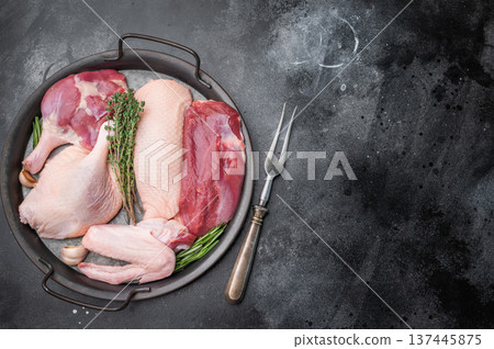 Fresh uncooked duck assortment arranged with thyme rosemary and garlic in rustic pan against textured dark surface perfect for culinary visuals. Fresh uncooked duck assortment arranged with thyme rosemary and garlic in rustic pan against textured dark surface perfect for culinary visuals. 137445875