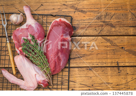 Fresh uncooked duck cuts breast fillet thigh and wingarranged on cooling grid against scratched wood surface perfect for culinary preparation visuals. Fresh uncooked duck cuts breast fillet thigh and wingarranged on cooling grid against scratched wood surface perfect for culinary preparation visuals. 137445878