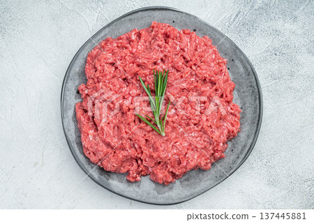 Uncooked raw minced pork and beef meat slab with herbs and pepper on rustic board highlighting raw texture for culinary and food preparation visuals. 137445881
