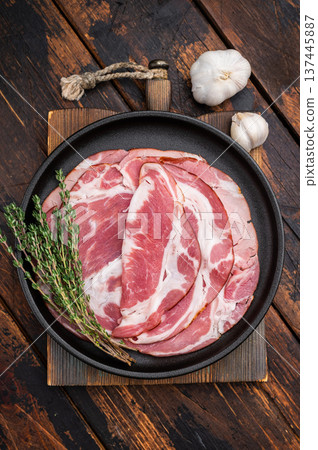 Spanish lomo slices with rosemary on a dark plate served on a wooden dark background for food stock. 137445887