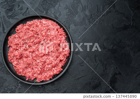 Fresh raw ground mince beef and pork meat with seasoning on black plate over dark textured background ideal for cooking, butcher and protein ingredient themes. 137445890