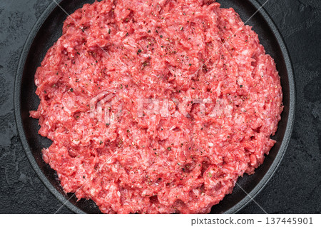 Fresh raw ground mince beef and pork meat with seasoning on black plate over dark textured background ideal for cooking, butcher and protein ingredient themes. 137445901