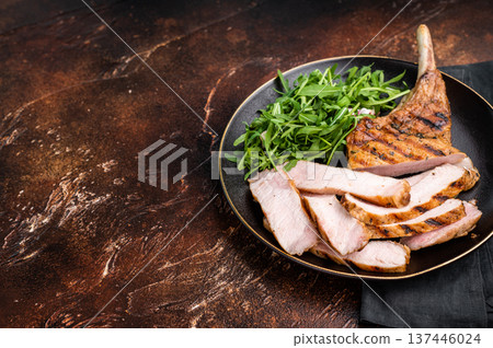 Succulent grilled Tomahawk pork chop, rib bone in steak featuring crispy edges and juicy meat that will tantalize your taste buds. brown background. top view Succulent grilled Tomahawk pork chop, rib bone in steak featuring crispy edges and juicy meat that will tantalize your taste buds. brown background. top view 137446024