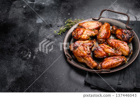Savory grilled chicken wings smothered in tangy barbecue sauce, the ultimate treat for meat lovers and party enthusiasts. black background. top view Savory grilled chicken wings smothered in tangy barbecue sauce, the ultimate treat for meat lovers and party enthusiasts. black background. top view 137446043
