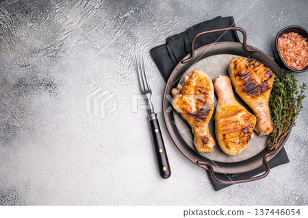 Juicy grilled chicken drumsticks, perfectly charred and bursting with flavor, ideal for a summer barbecue. grey background. top view 137446054